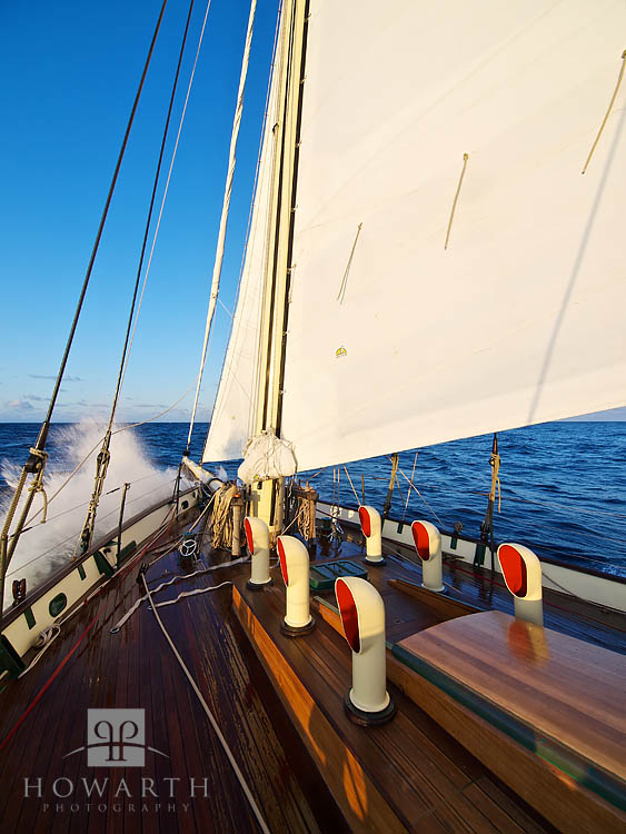 The late afternoon sun hits the ship just as a splash comes over the bow