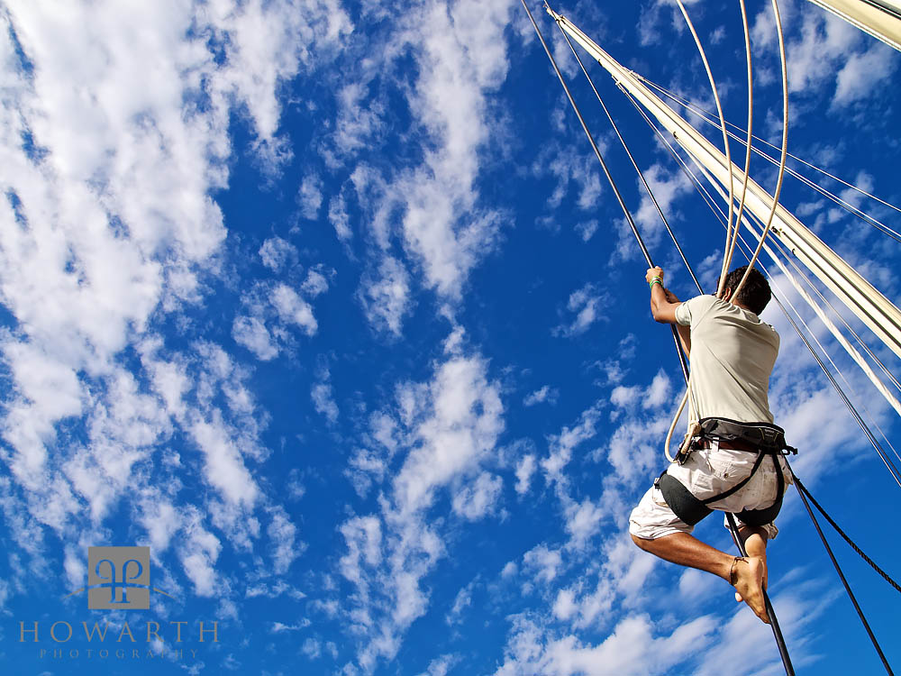 A sailor hoists himself up the rigging of spirit under the clear blue skies