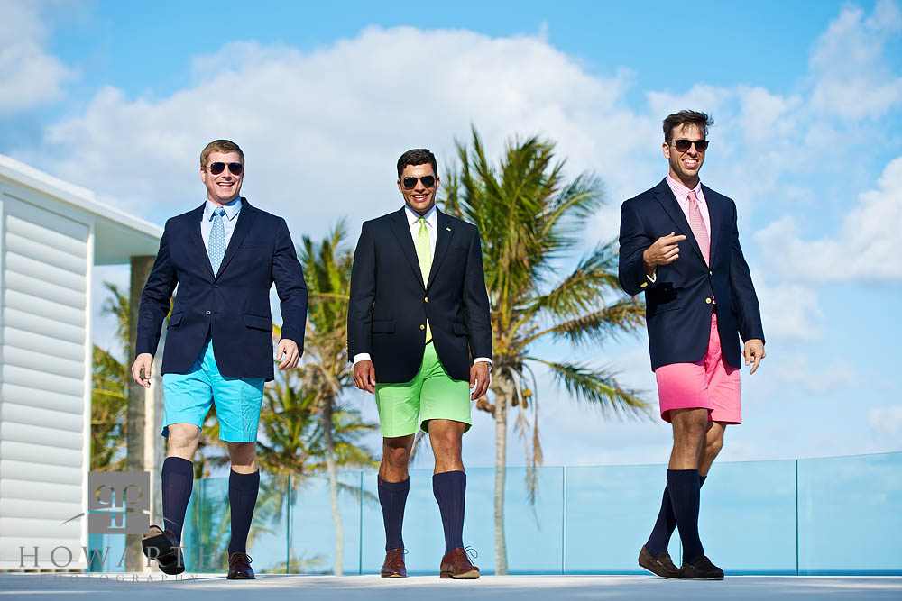 Three young professionals walking together; smiling and laughing while wearing brightly colored blue, green and pink Bermuda...