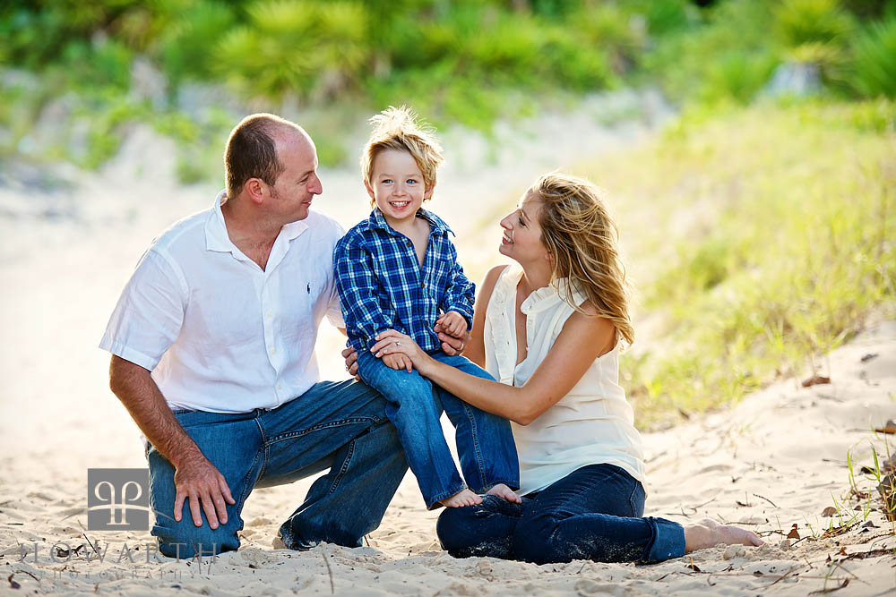 Portrait of a Mother, Father and Young Son sitting on the trails in the shade.