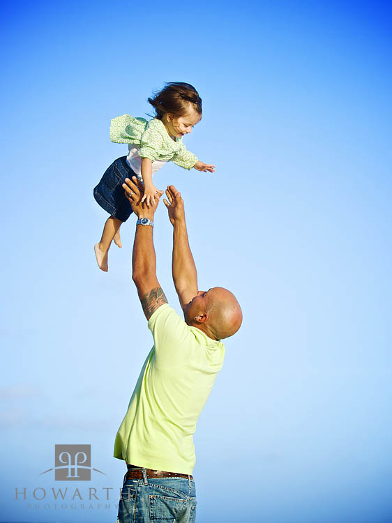 Father throwing his young laughing daughter in the air and reaching out to catch her