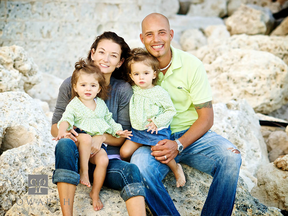 Portrait of a smiling Mother and Father sitting on the limestone rocks with their young twin daughters