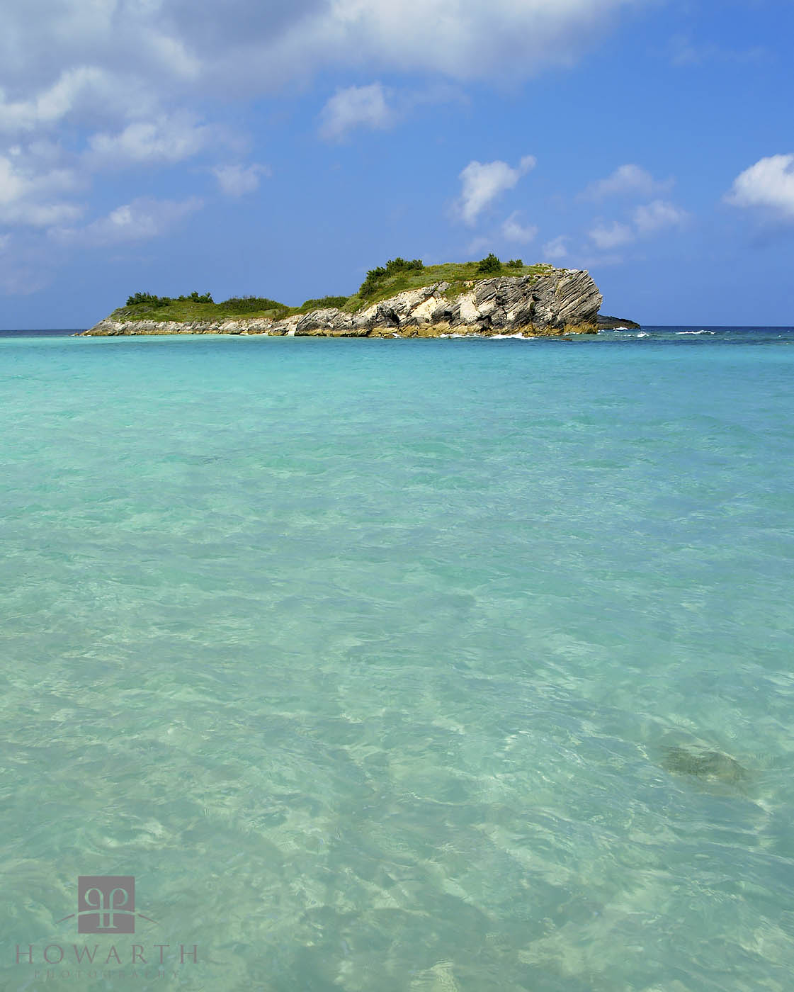 Turquoise waters lead to Charles Island under blue skies