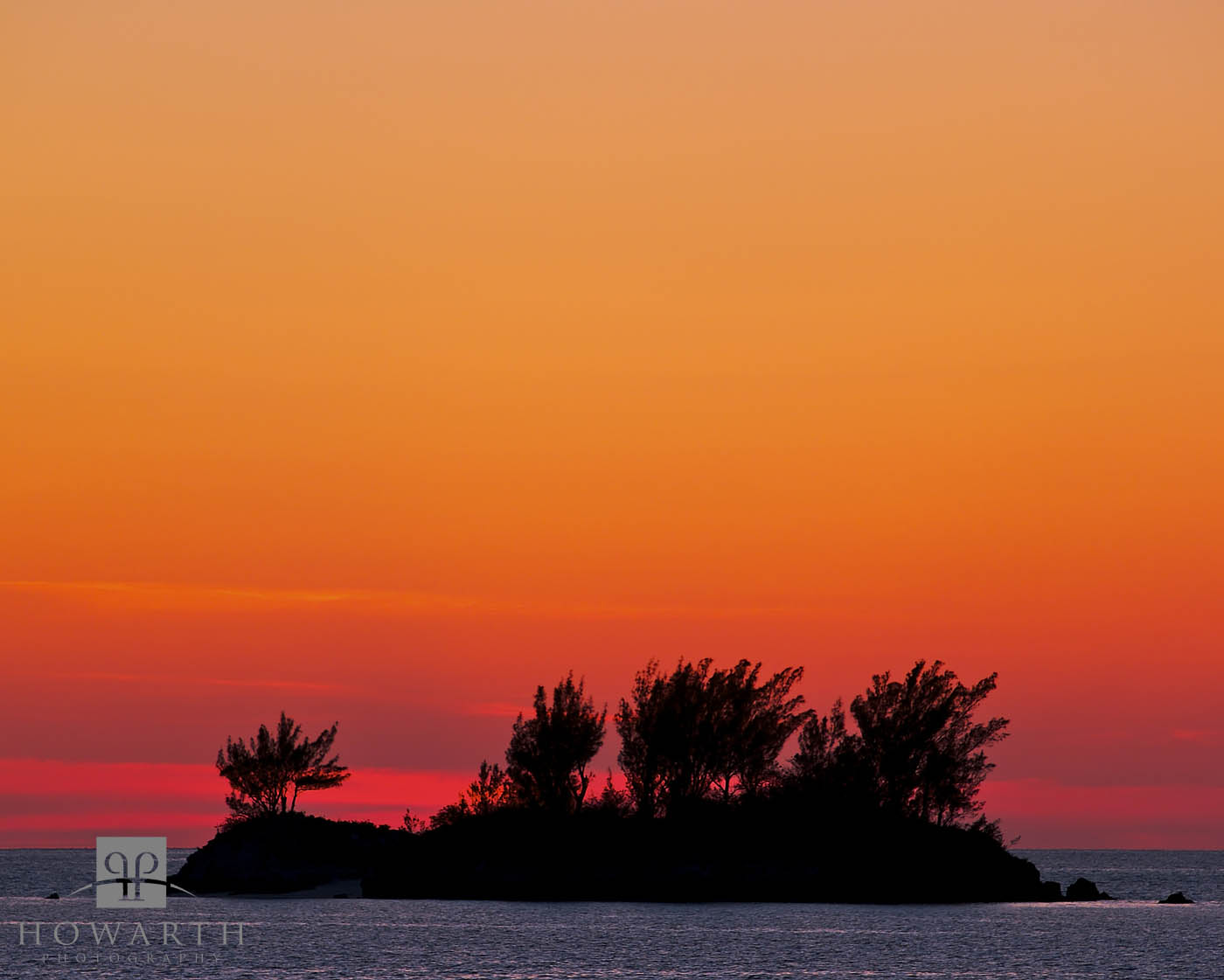 The islands of kings point silhouetted against the orange glow of a sunset