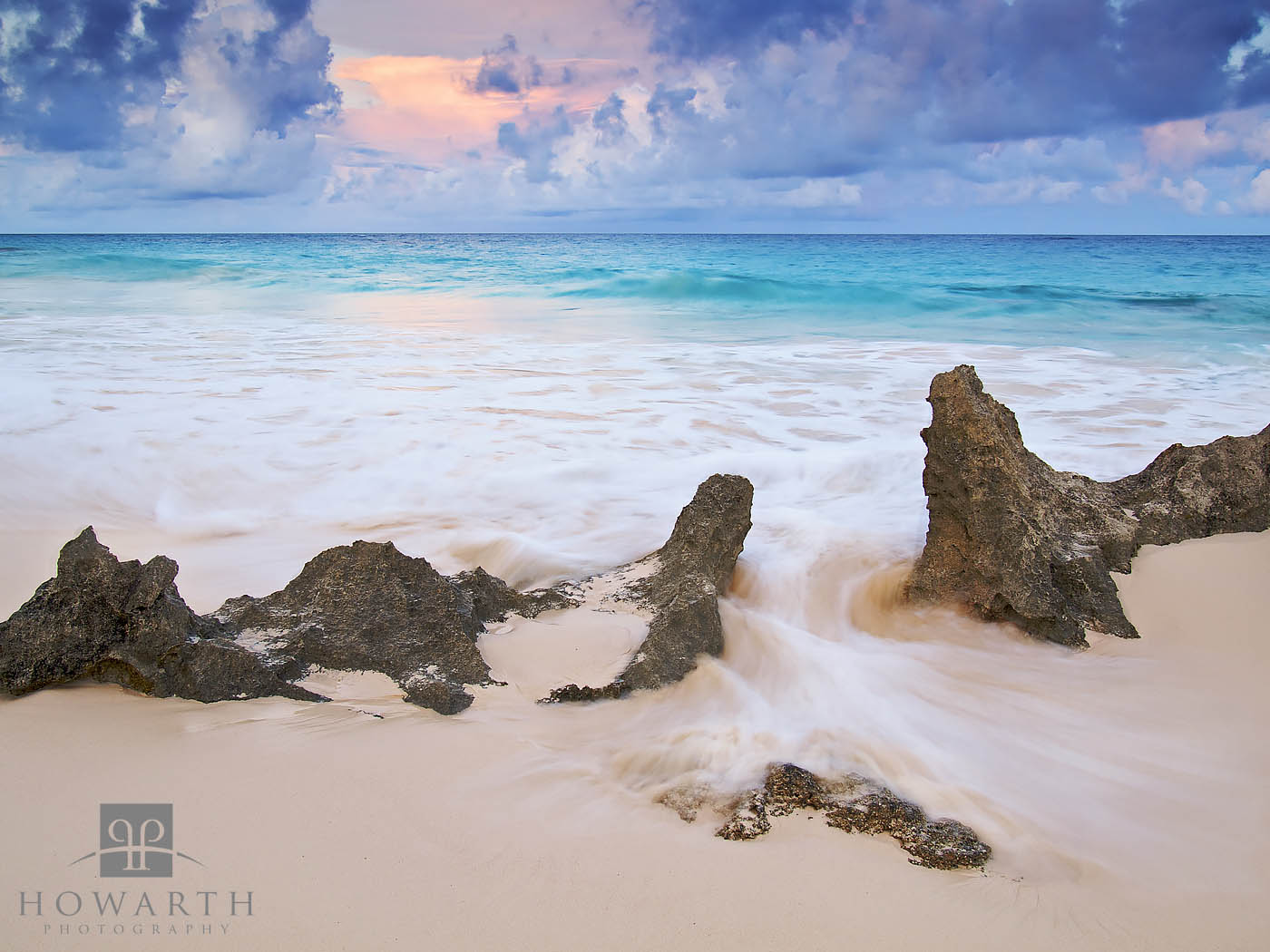 A small cluster of rocks with an incoming rush of water under the evening light