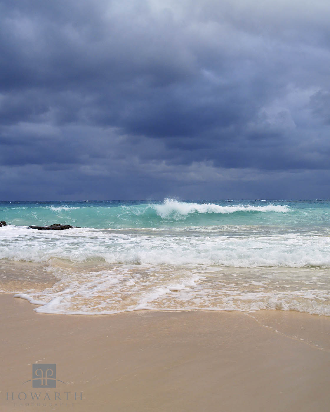 Heavy clouds build offshore as the surf rolls in